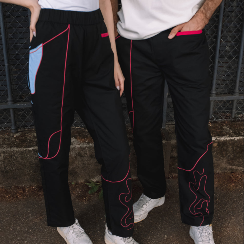 Two people standing side by side, wearing matching black pants with colorful outlines.